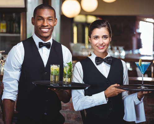 Mixed race waiter and waitress holding a serving tray